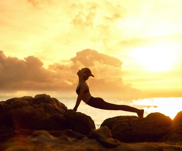 Silhouette of a person in a yoga pose against a sunset.